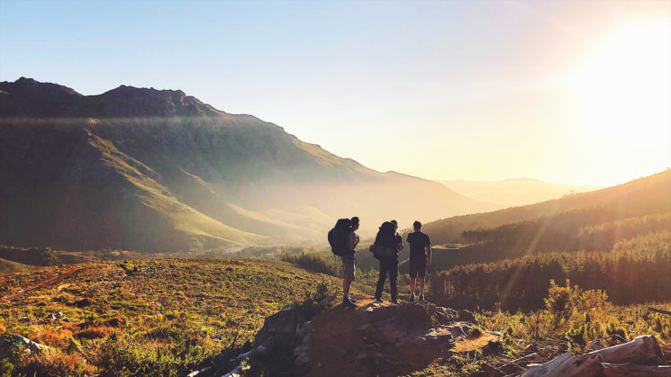 Rearview of Hikers with backpacks enjoying the sunset in the mountains